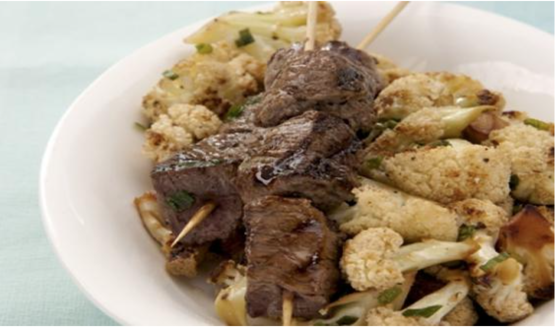 Brochetas de carne con coliflor salteada y ensalada de alubias con pipirrana